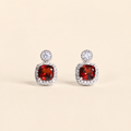Natural garnet halo stud earrings on a warm ivory background