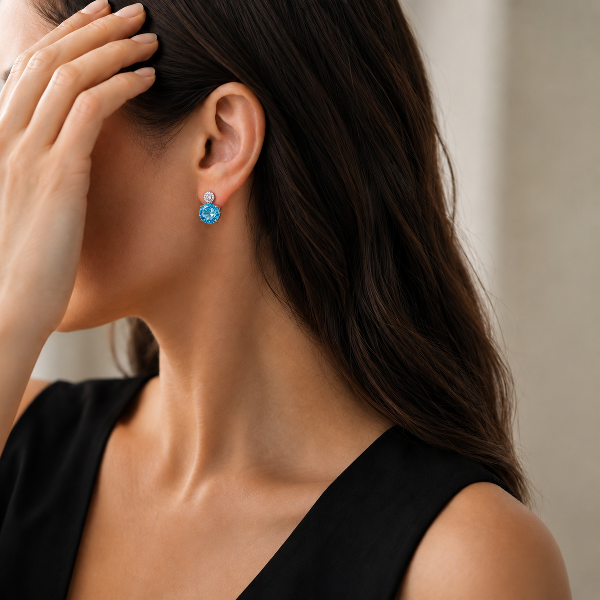 Natural Swiss blue topaz stud earring styled with a black dress on a model