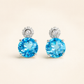 Natural Swiss blue topaz stud earrings on a warm ivory background